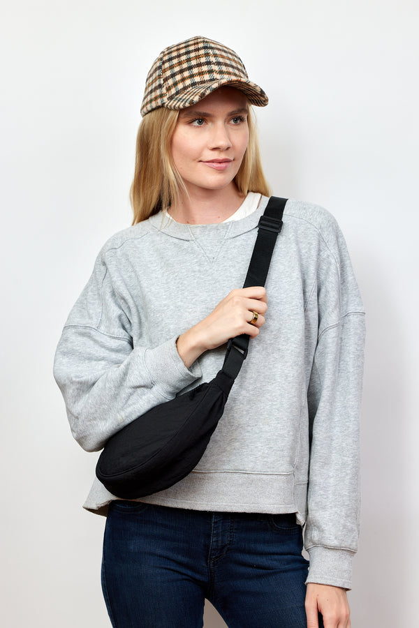 Model wearing black nylon crossbody bag and holding strap