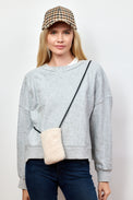 Model wearing ivory sherpa phone bag with crossbody strap and plaid baseball cap