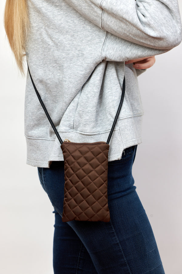 Model wearing brown quilted phone bag with crossbody strap