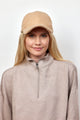 Woman wearing a tan sherpa cap and taupe pullover half zip sweatshirt