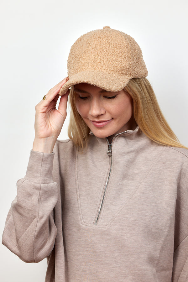 Woman wearing a tan sherpa cap and taupe pullover