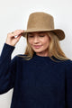 Model holding brim of camel brown velour brimmed hat