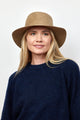 Model wearing camel brown velour brimmed hat and navy sweater