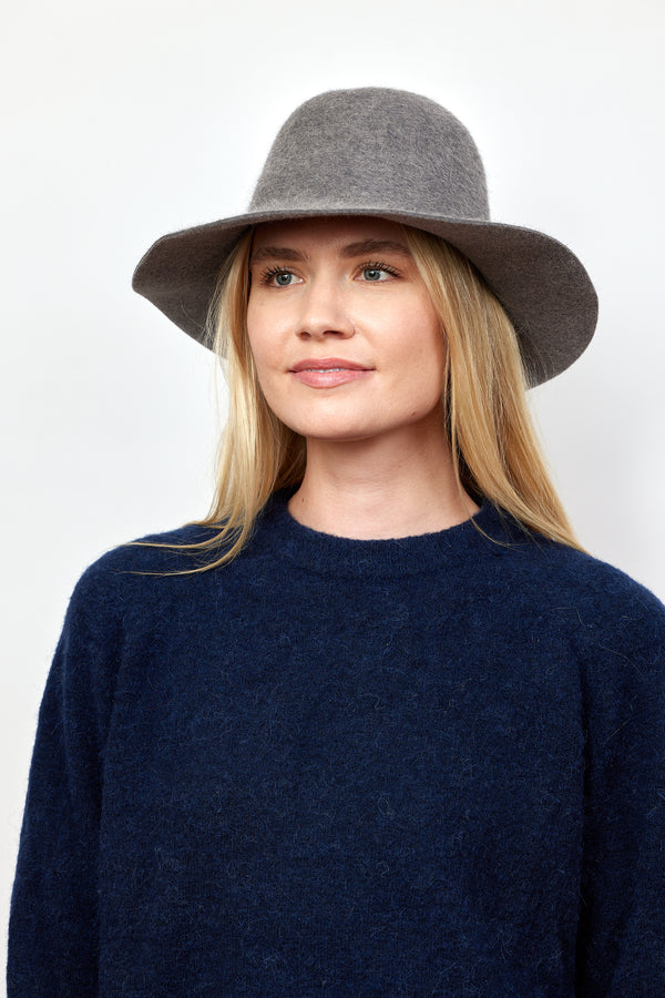 Model wearing grey velour brimmed hat and looking to her right