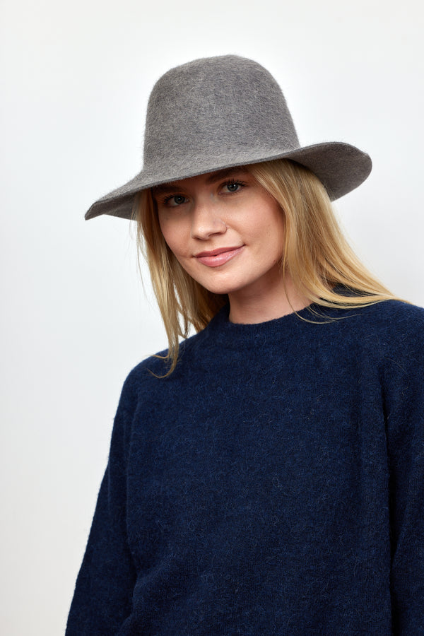 Grey velour brimmed hat on model wearing navy sweater