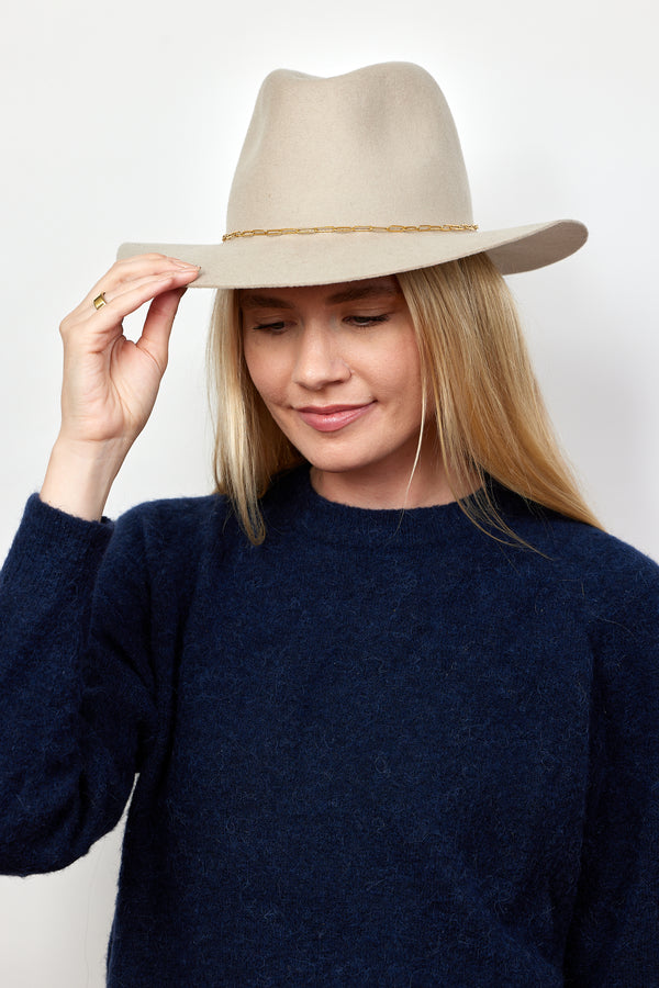 Beige wool felt hat with gold chain trim on model