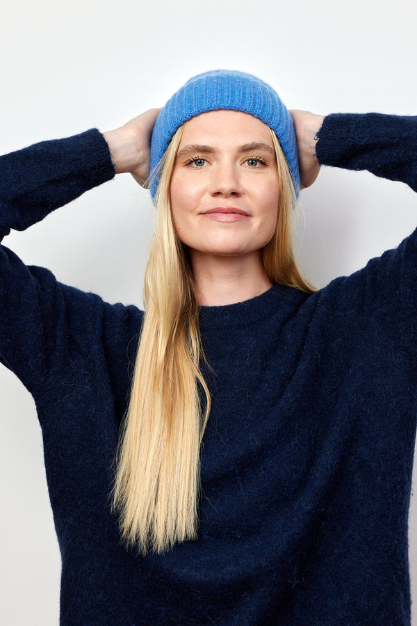 Denim blue cashmere rib beanie on model with arms on head