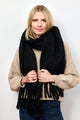 Model holding fringe of black scarf around neck