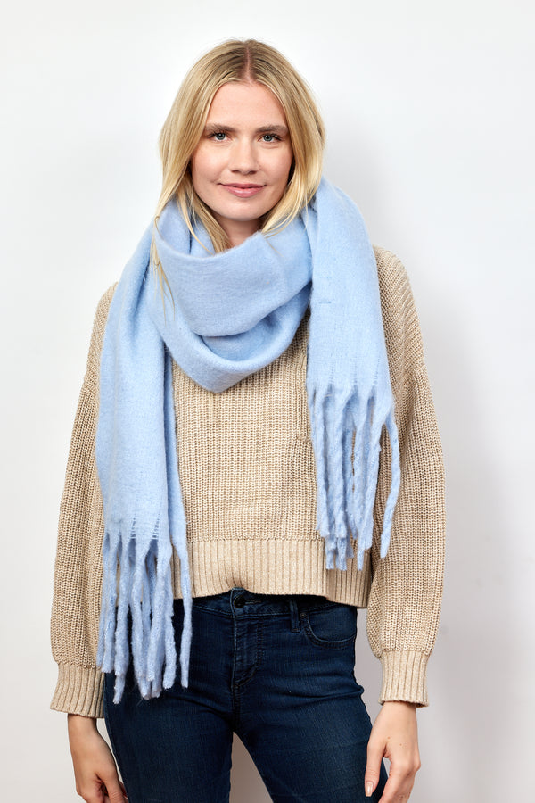 Light blue scarf on model wearing tan sweater and jeans