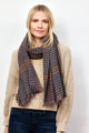 Model wearing brown and blue check pattern scarf with tan sweater