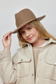 Model holding brim of taupe wool felt hat with tan tie