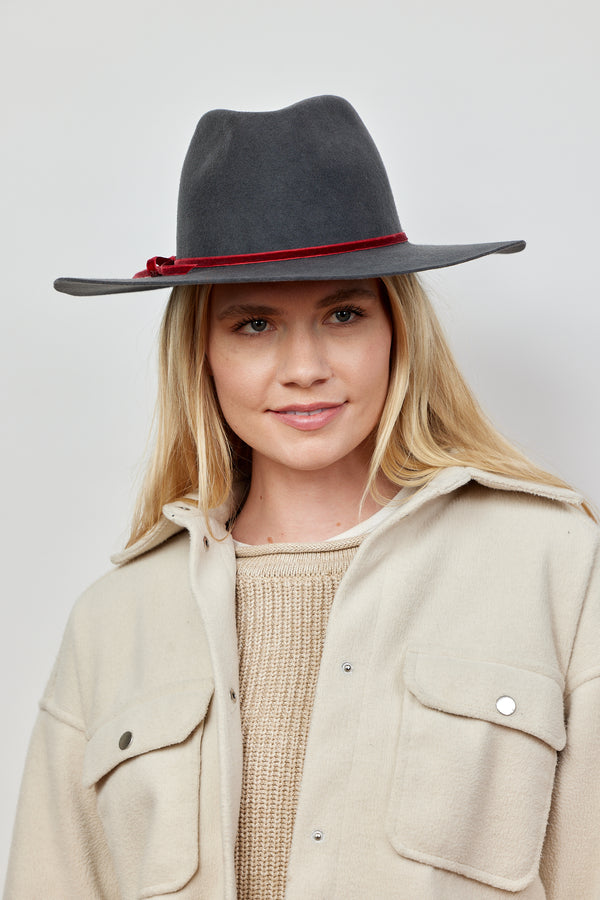 Model wearing charcoal wool felt brimmed hat with burgundy tie trim and tan sweater and jacket