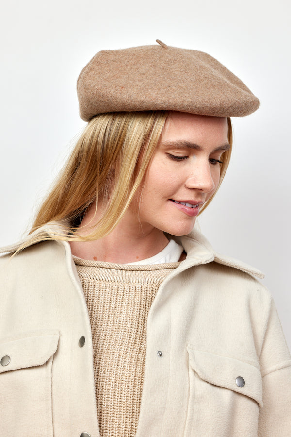 Model wearing taupe wool felt beret and tan jacket