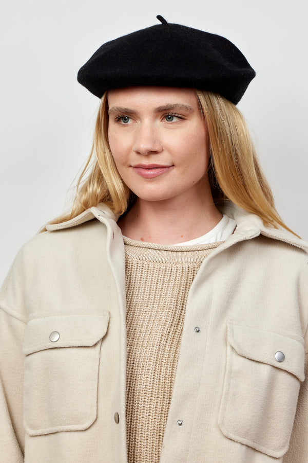 Model wearing black wool felt beret and tan jacket