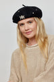 Model wearing black beret with crystal embellishments