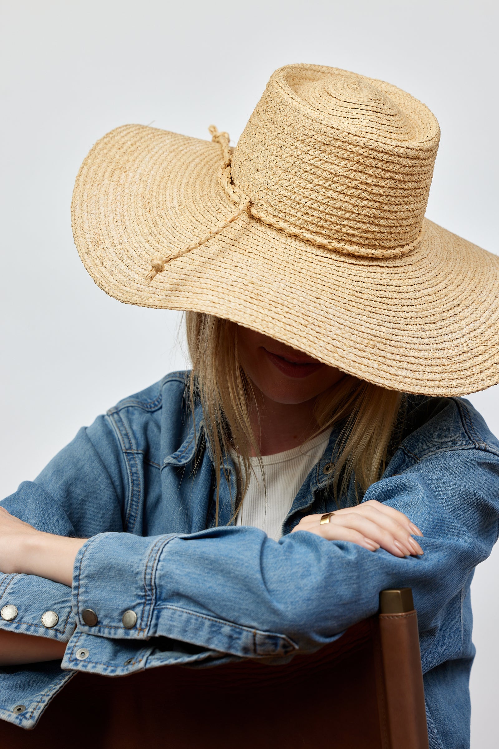Model wearing brimmed straw sun hat with straw trim