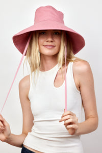 Model wearing pink canvas sun hat with chinstrap