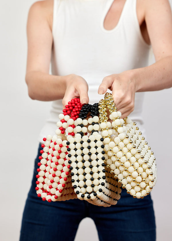 Model holding red, black and gold beaded bags