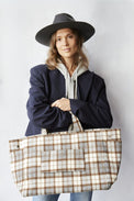 Woman holding a plaid tote bag against a plain background