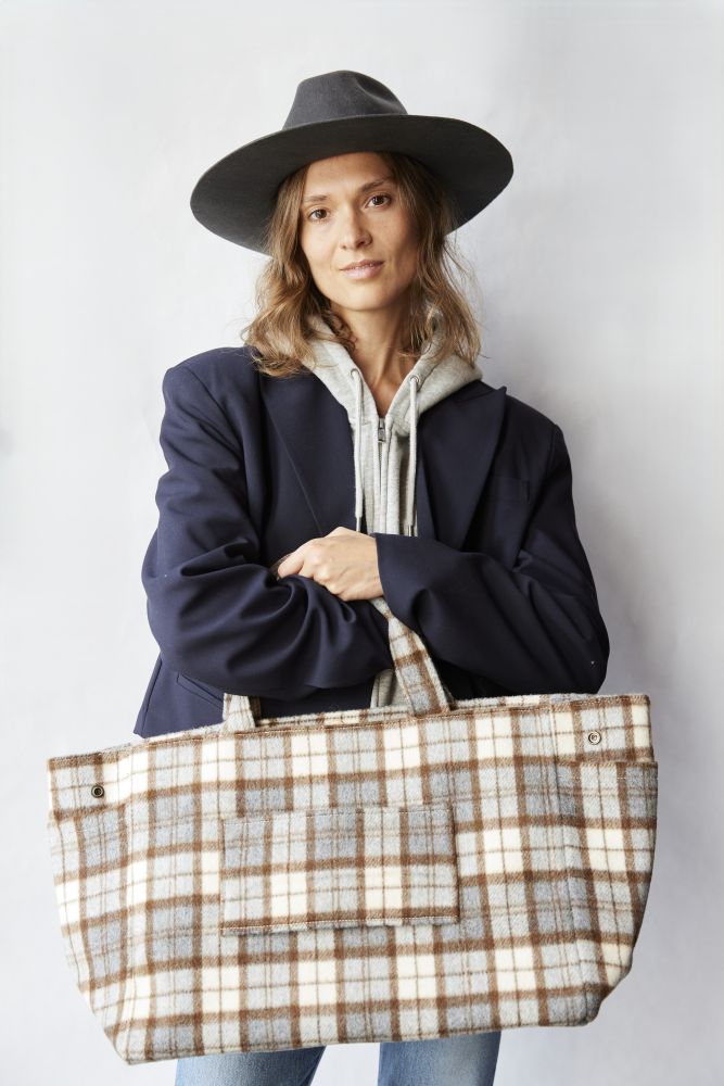 Woman holding a plaid tote bag against a plain background