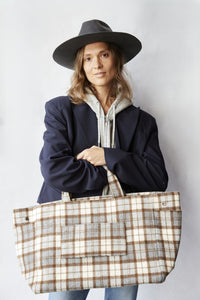 Woman holding a plaid tote bag against a plain background
