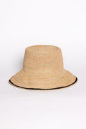 Beige straw bucket hat with black trim on a white background