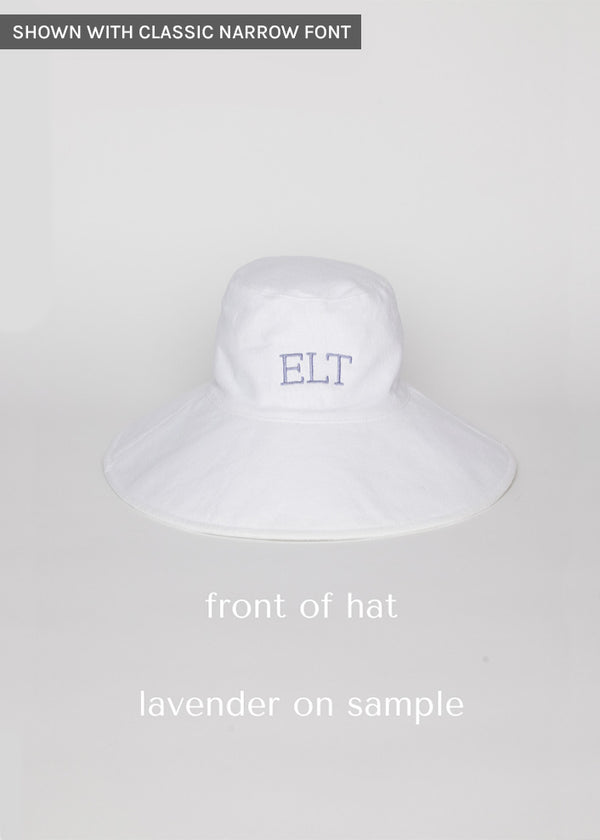 White packable hat with lavender embroidered letters