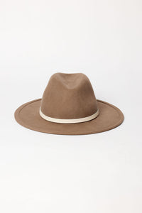Brown fedora hat with a white band on a light beige background