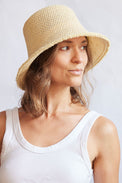 Woman wearing a woven bucket hat against a plain background