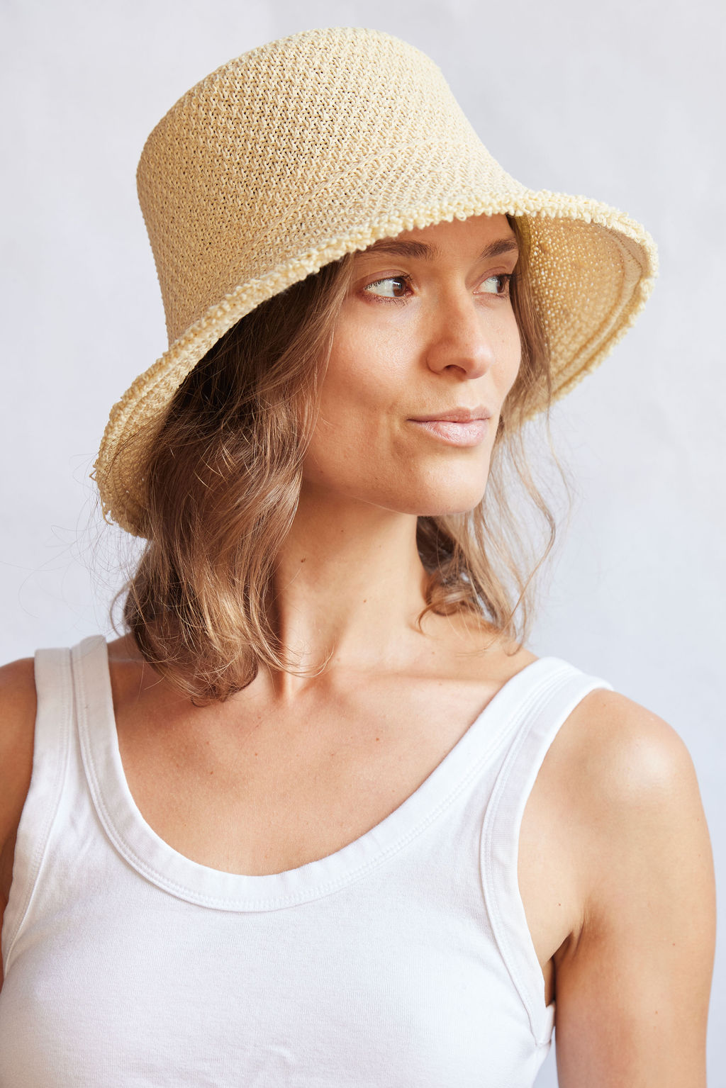 Woman wearing a woven bucket hat against a plain background