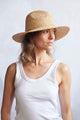 Woman wearing a straw hat against a plain background