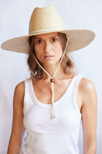Woman wearing a wide-brimmed straw hat with a white background