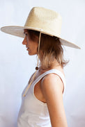 Woman wearing a wide-brimmed straw hat against a white background