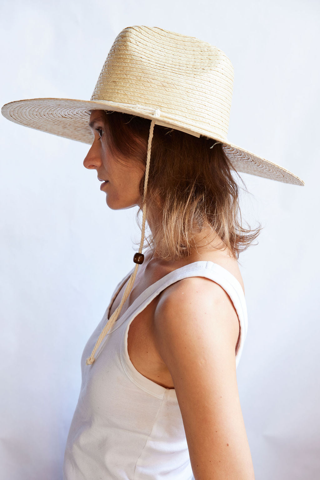 Woman wearing a wide-brimmed straw hat against a white background