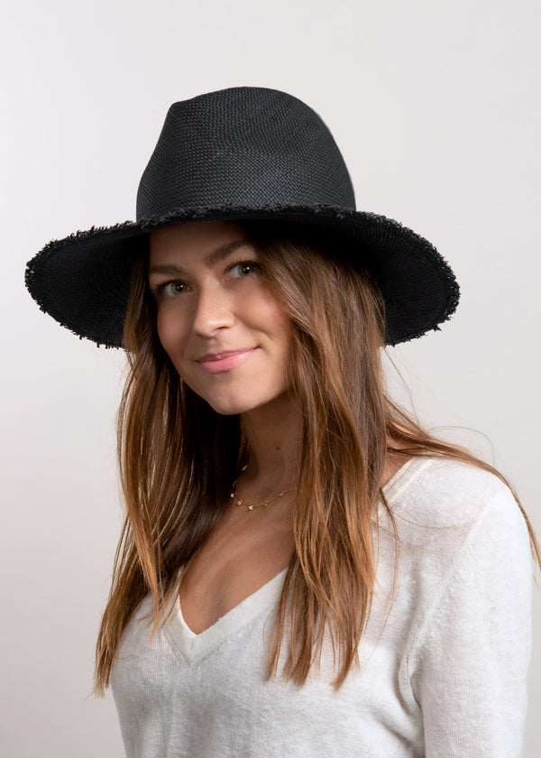 Model wearing black brimmed sun hat with fringed brim