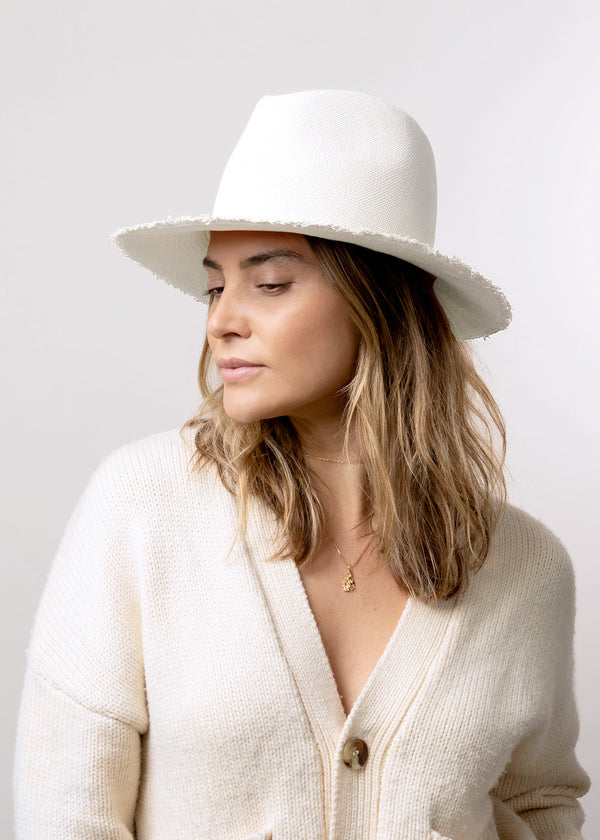 Model wearing white brimmed sun hat with fringed brim