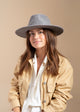 Model wearing grey velour brimmed hat and yellow jacket