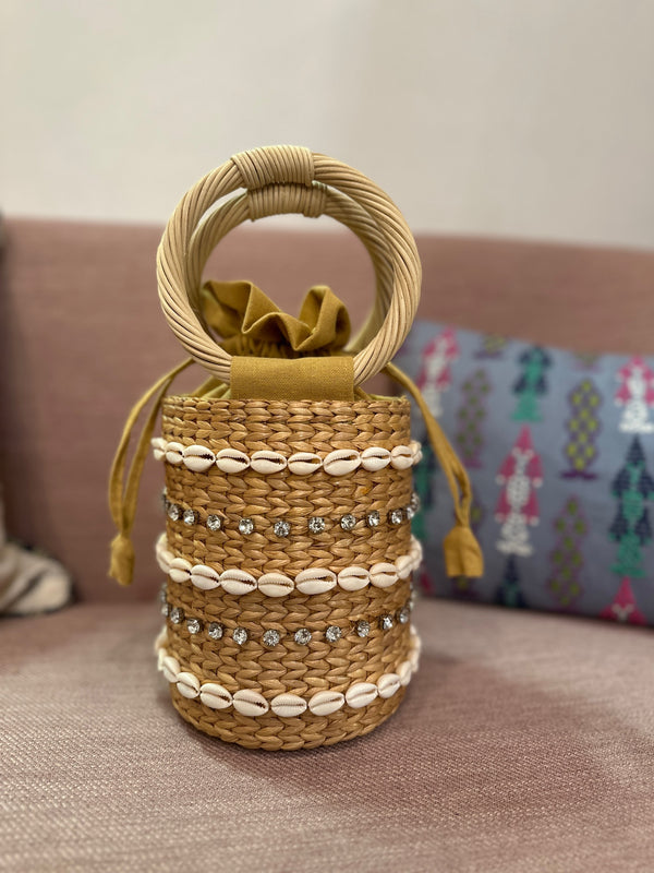 Small straw bag with shell and rhinestone detail sitting on chair