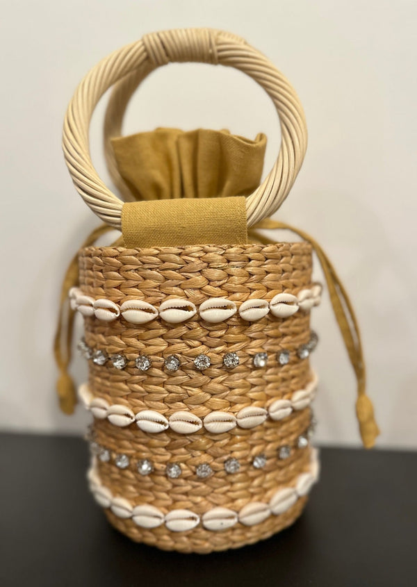 Close up of small straw back with round handle, shell and rhinestone detail