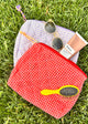 Red and lavender mini check bags with toiletries in the grass