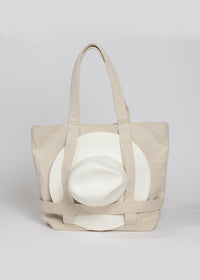 Tan canvas tote bag with white sun hat attached 
