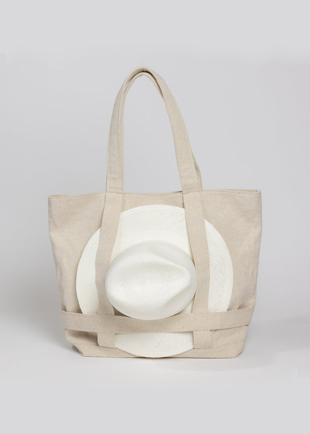 Tan canvas tote bag with white sun hat attached 