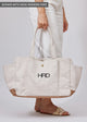 Model holding embroidered tote bag with pockets
