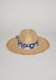 Front view of straw hat with fringe detail on brim and blue floral fabric trim