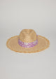 Front view of straw hat with fringe detail on brim and lavender floral fabric trim