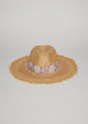 Front view of straw hat with fringe detail on brim and tan floral fabric trim