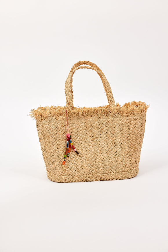 Woven straw bag with colorful charm on a white background
