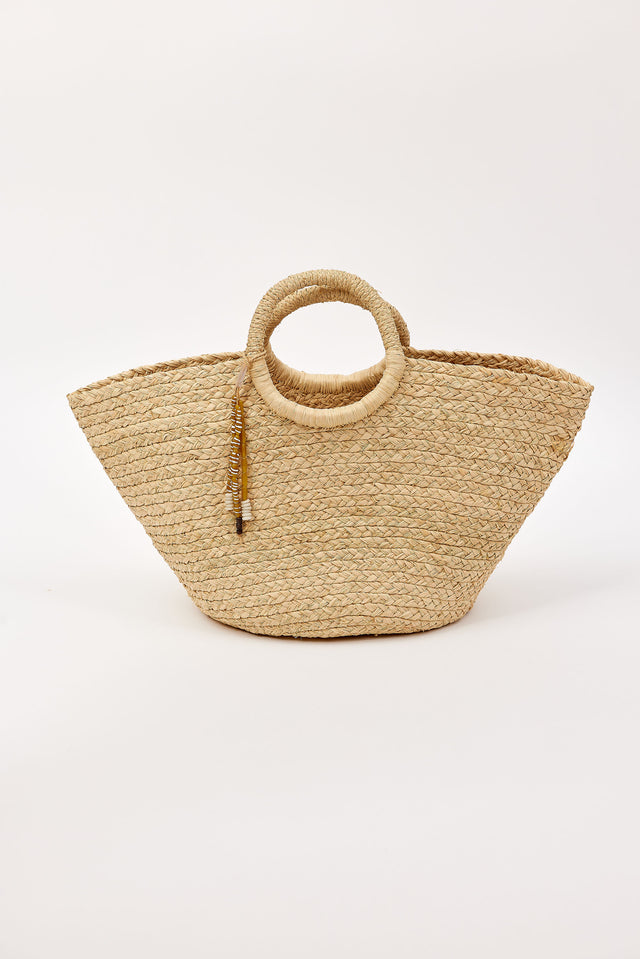 Woven straw bag with circular handles and tassel detail on a white background