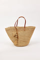 Woven straw bag with leather handle and tassel on a white background