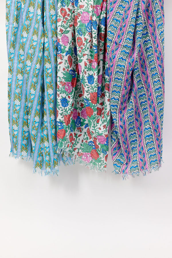 Three colorful scarves with floral and geometric patterns on a white background